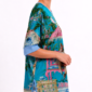 Frontansicht eines Oversize Shirts mit V Ausschnitt und hellblauen Bündchen. Chinoiserie Digitalprint mit Affe unter rosa Strass Sonnenschirm auf Gartenbank im Porzellanmuster, vollflächiger Strassbesatz an Schirm und Bank, umrahmt von floralem Blütenzweig Muster auf türkisem Untergrund. AA Maß 97 cm, Länge ab Schulter 73 cm, Einheitsgröße. 70% Baumwolle, 28% Polyester, 2% Elasthan. Oversize Affenmotiv Shirt Großhandel bei rosemodee.de, Deutschland.